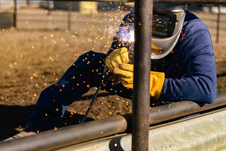 Welder in OUTRIDER gloves working a corral rail